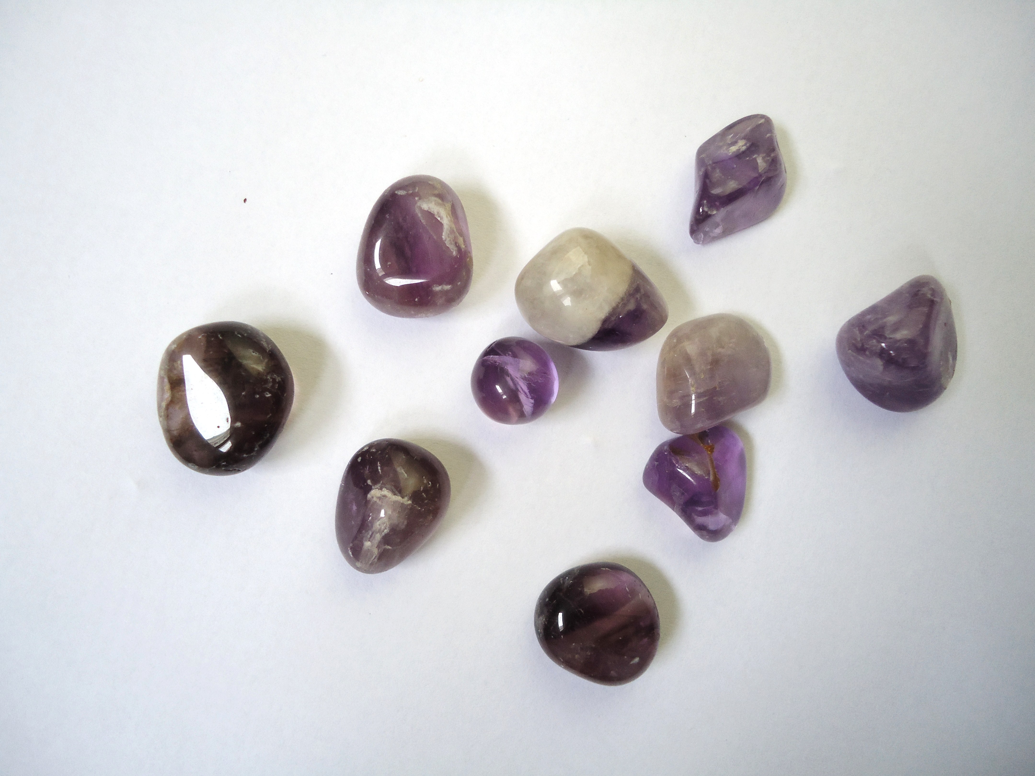 Tumbled amethyst stones in pale to deep purple on white