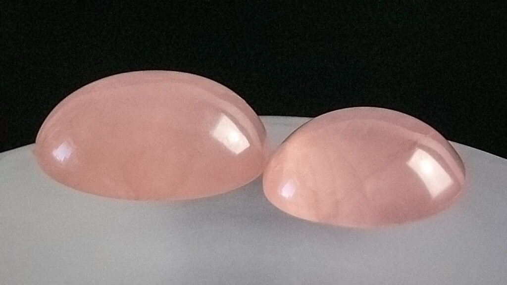 Two rose quartz cabochons showing the stone even, soft pink colour