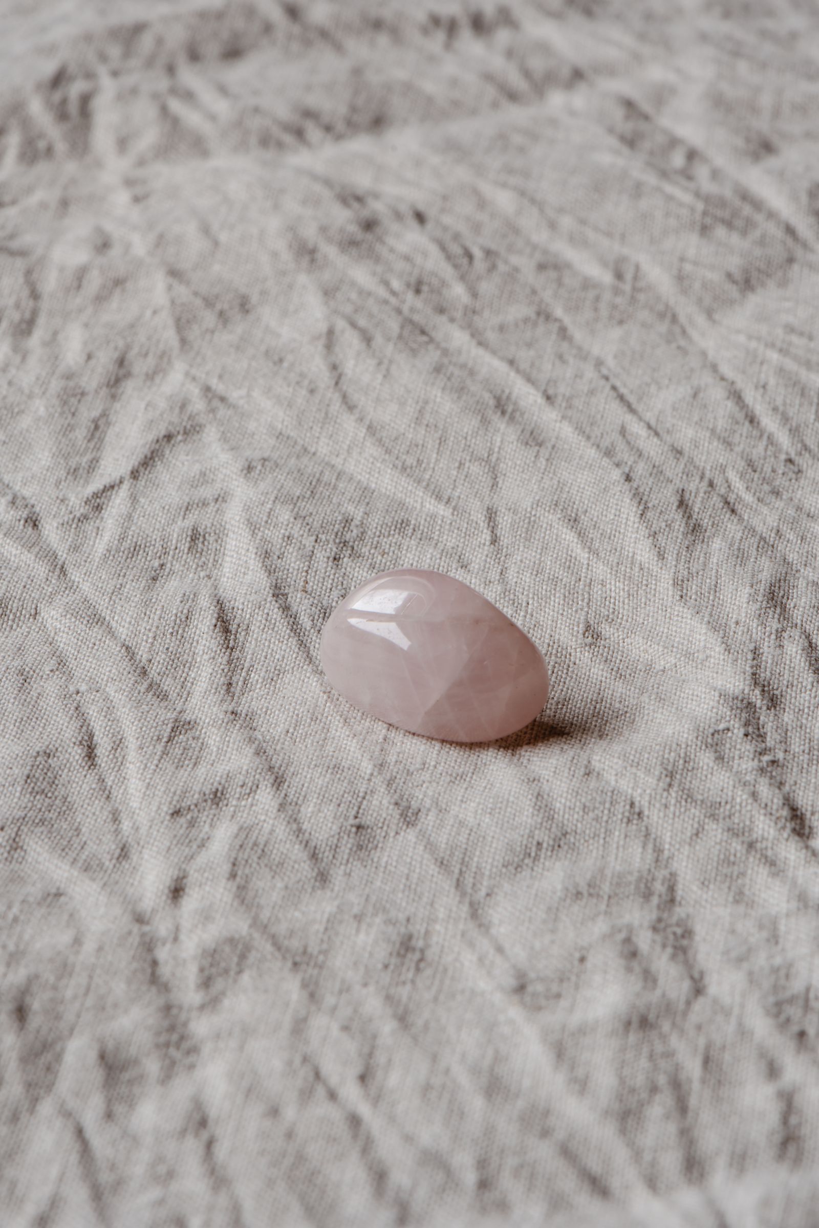 Single rose quartz tumbled stone on fabric